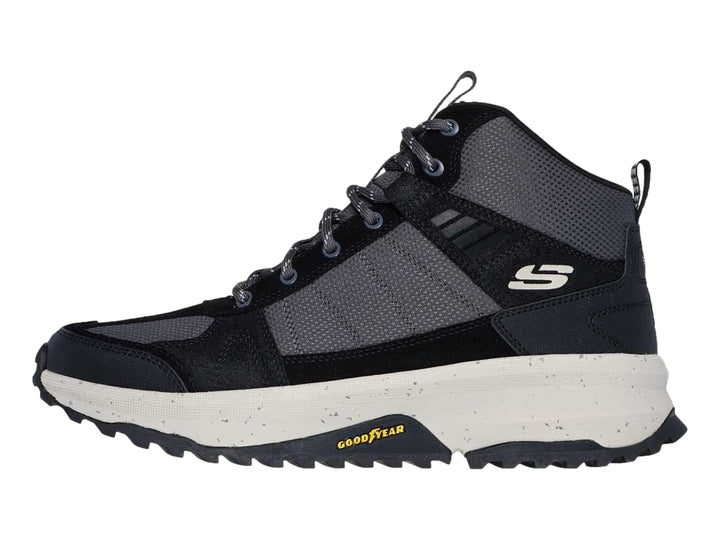 Bota deportiva Skechers en color negro y gris con suela blanca gruesa y tracción para actividades al aire libre.