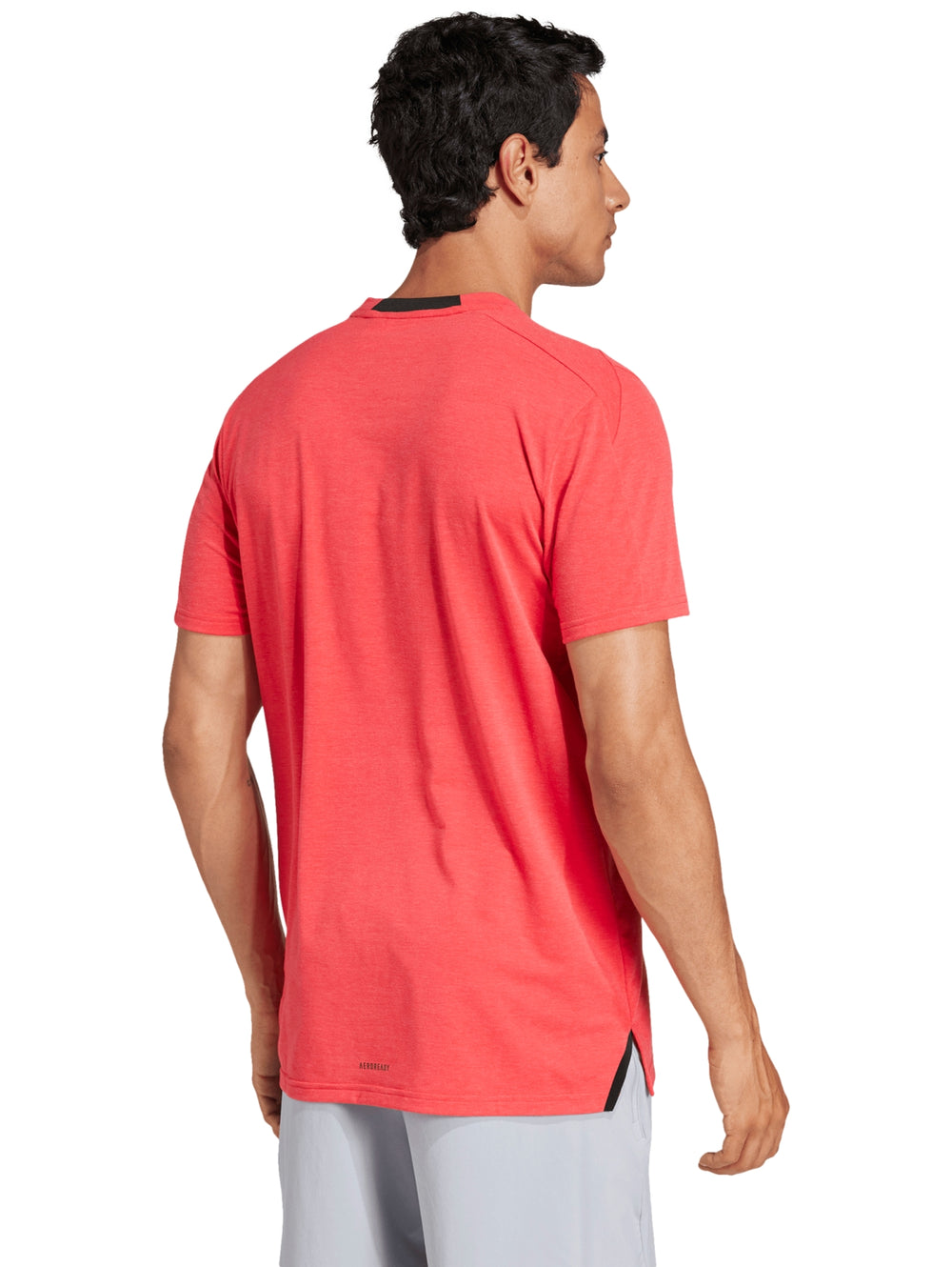 Hombre vistiendo una playera Adidas de color Pure Ruby con logo pequeño en el pecho y cuello redondo.