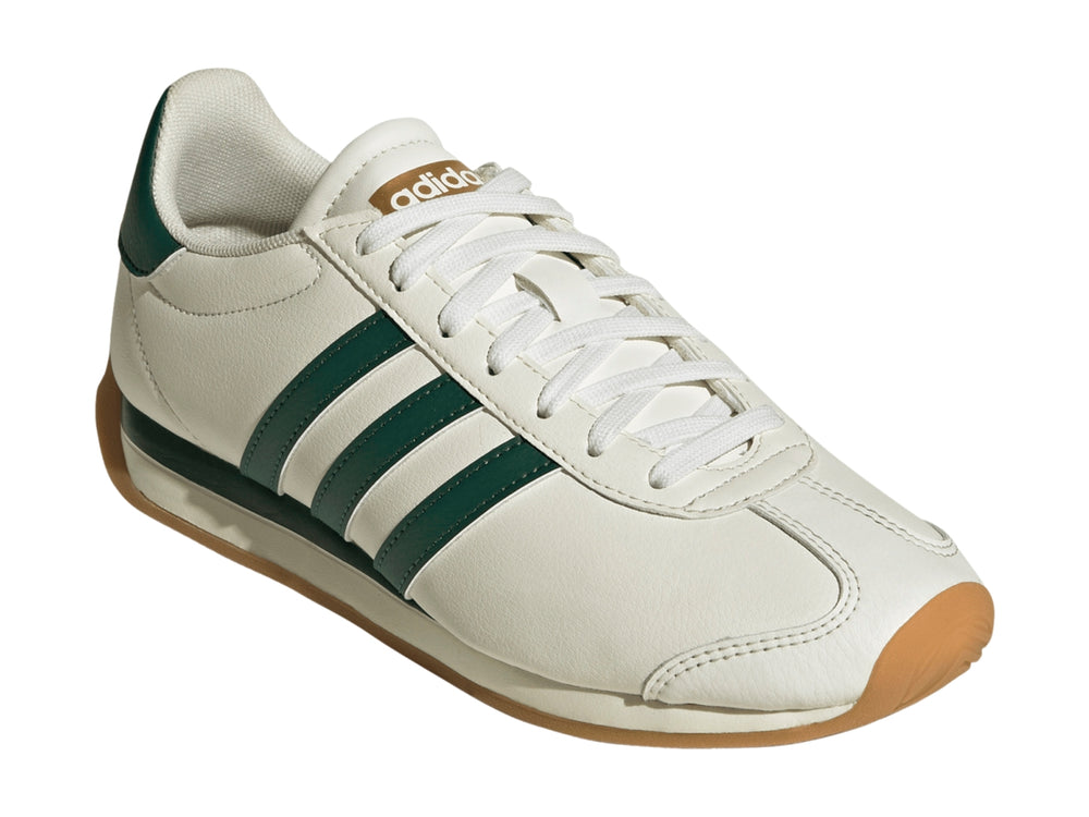Tenis Adidas Runvista color blanco roto con tres franjas verdes y suela de goma marrón.