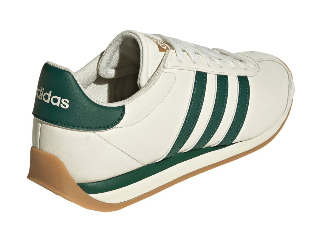 Tenis Adidas Runvista color blanco roto con tres franjas verdes y suela de goma marrón.