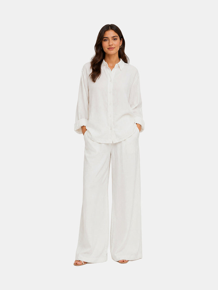 Mujer vistiendo un conjunto de dos piezas color blanco compuesto por camisa y pantalón de pierna ancha.