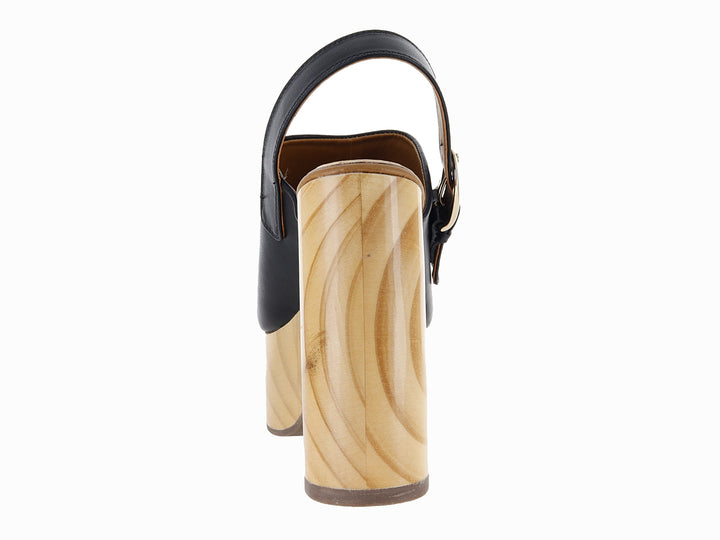Sandalia de plataforma con tacón grueso color madera y correa de cuero negro con hebilla dorada.