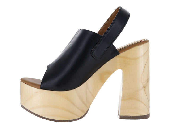 Sandalia de plataforma con tacón grueso color madera y correa de cuero negro con hebilla dorada.