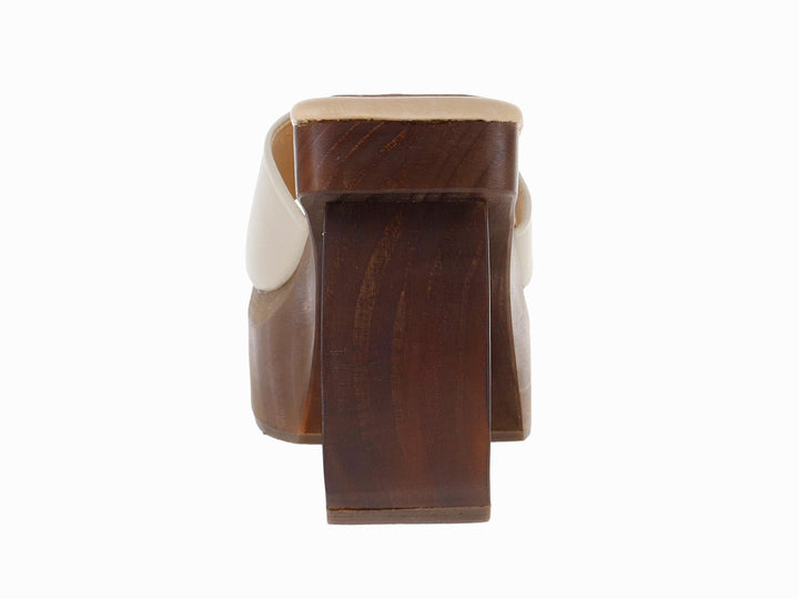 Sandalia de plataforma alta en color hueso con tacón esculpido de madera marrón.