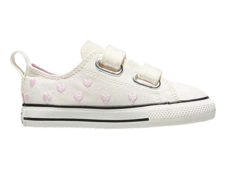 Tenis Converse color hueso con corazones rosas y cierres de velcro.