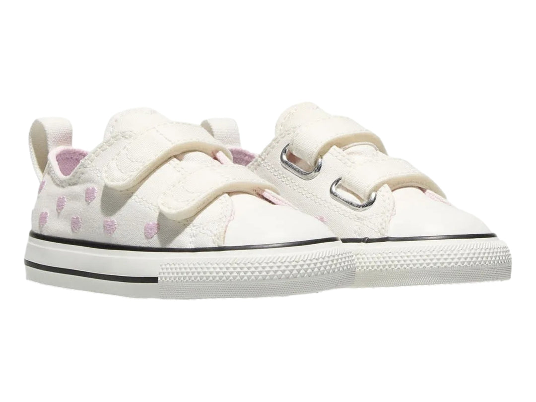 Tenis Converse color hueso con corazones rosas y cierres de velcro.