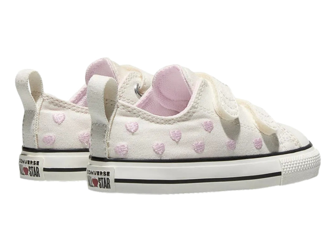 Tenis Converse color hueso con corazones rosas y cierres de velcro.