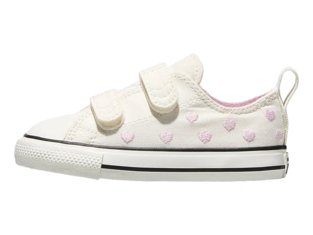 Tenis Converse color hueso con corazones rosas y cierres de velcro.