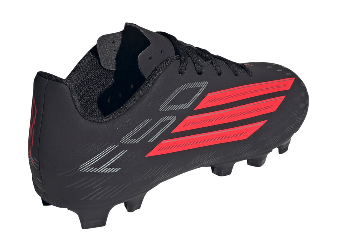 Zapato de fútbol Adidas F50 Club color negro con tres franjas rojas laterales y suela de tacos.