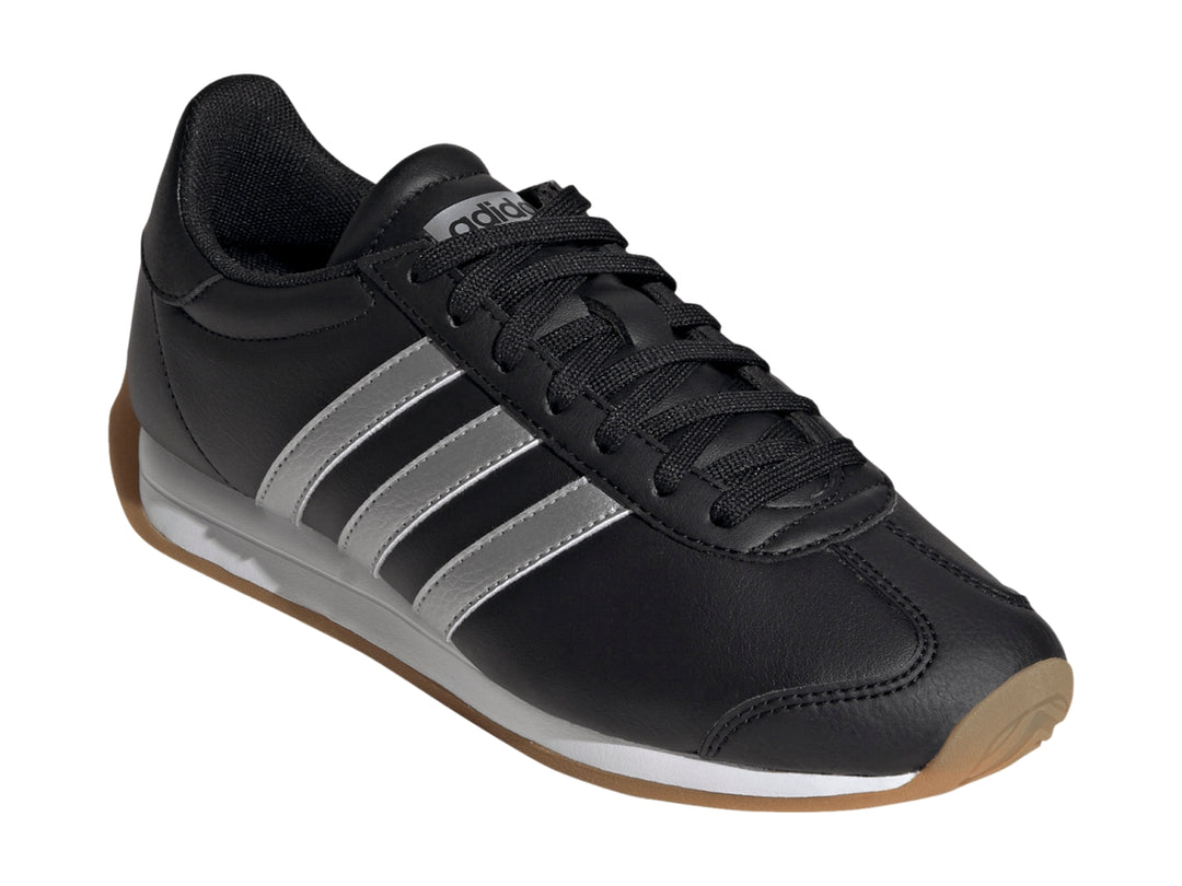 Tenis Adidas negros con tres franjas plateadas, entresuela blanca y suela de goma color café.