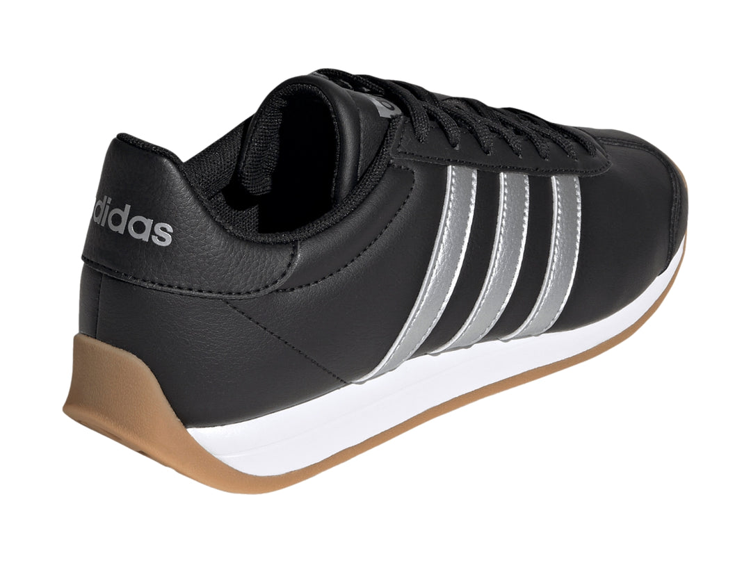 Tenis Adidas negros con tres franjas plateadas, entresuela blanca y suela de goma color café.
