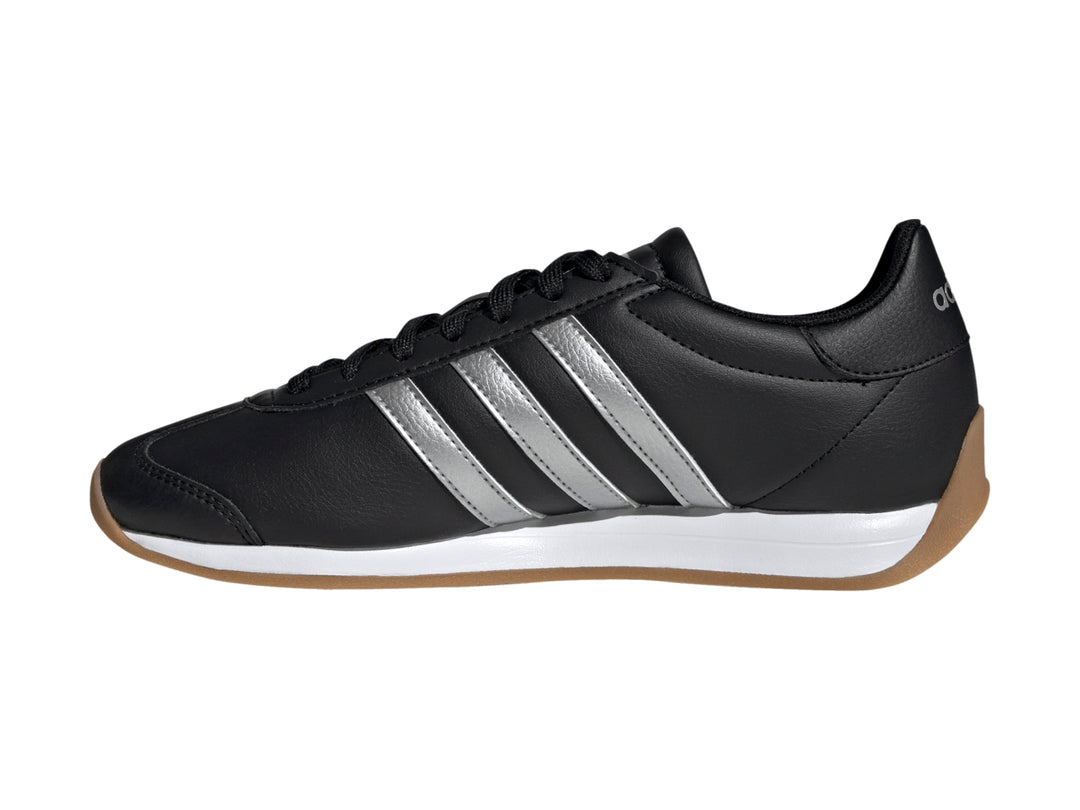 Tenis Adidas negros con tres franjas plateadas, entresuela blanca y suela de goma color café.