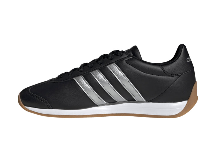 Tenis Adidas negros con tres franjas plateadas, entresuela blanca y suela de goma color café.
