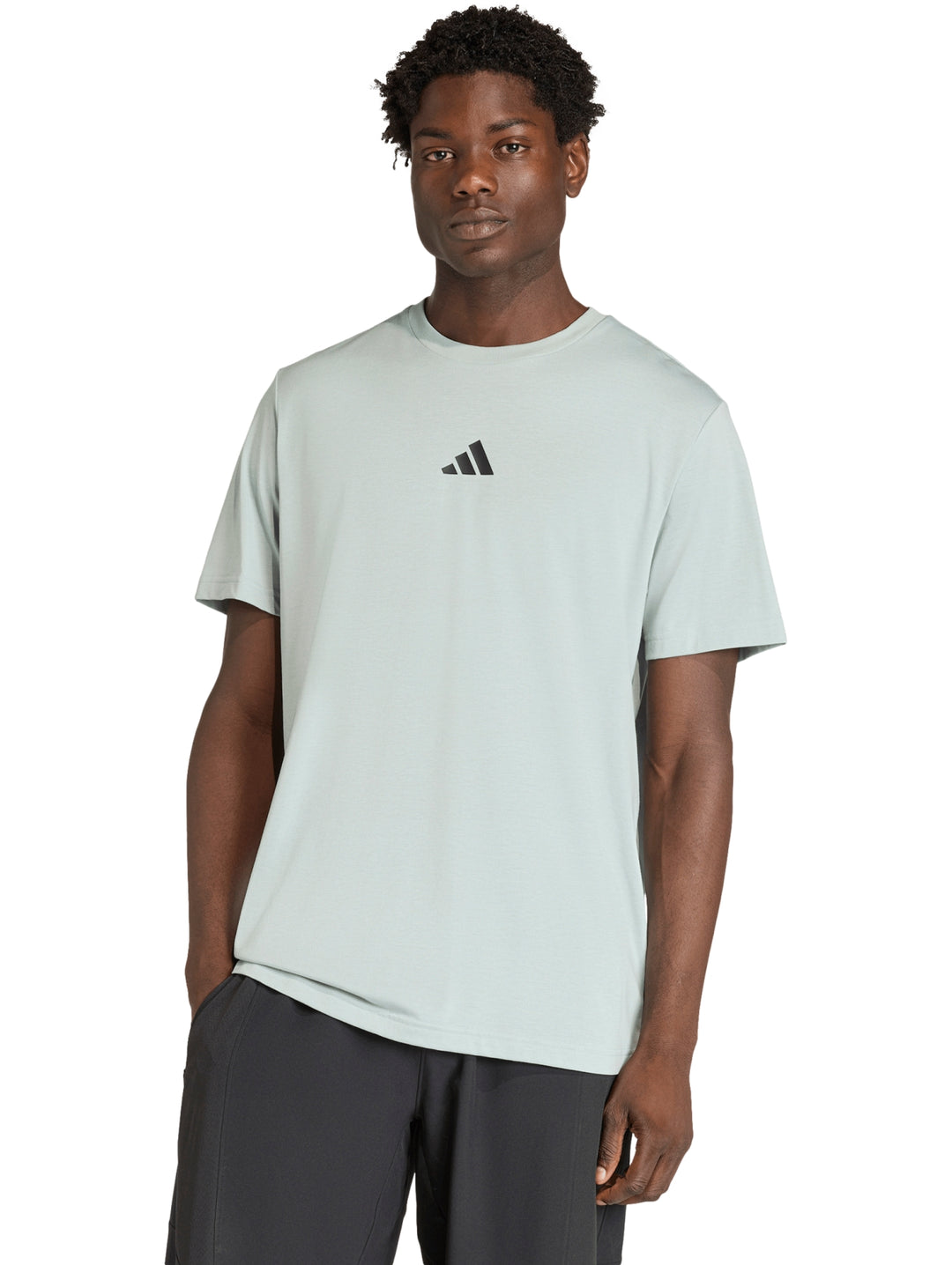 Hombre vistiendo camiseta deportiva Adidas color verde Wonder Sage con logo negro en el pecho.
