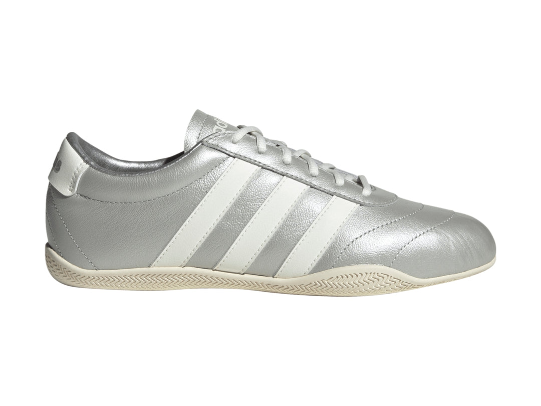Tenis Adidas Grand Court Low en color plata metálico con tres franjas blancas laterales y suela blanca.