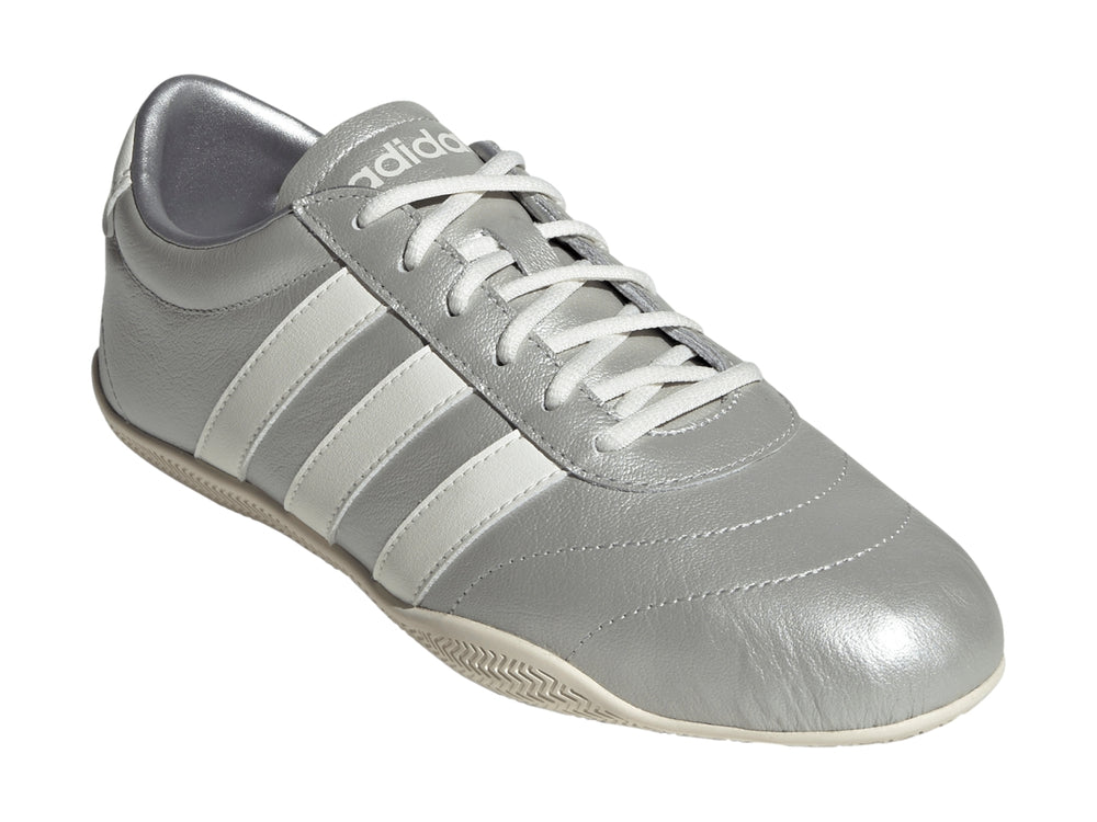 Tenis Adidas Grand Court Low en color plata metálico con tres franjas blancas laterales y suela blanca.