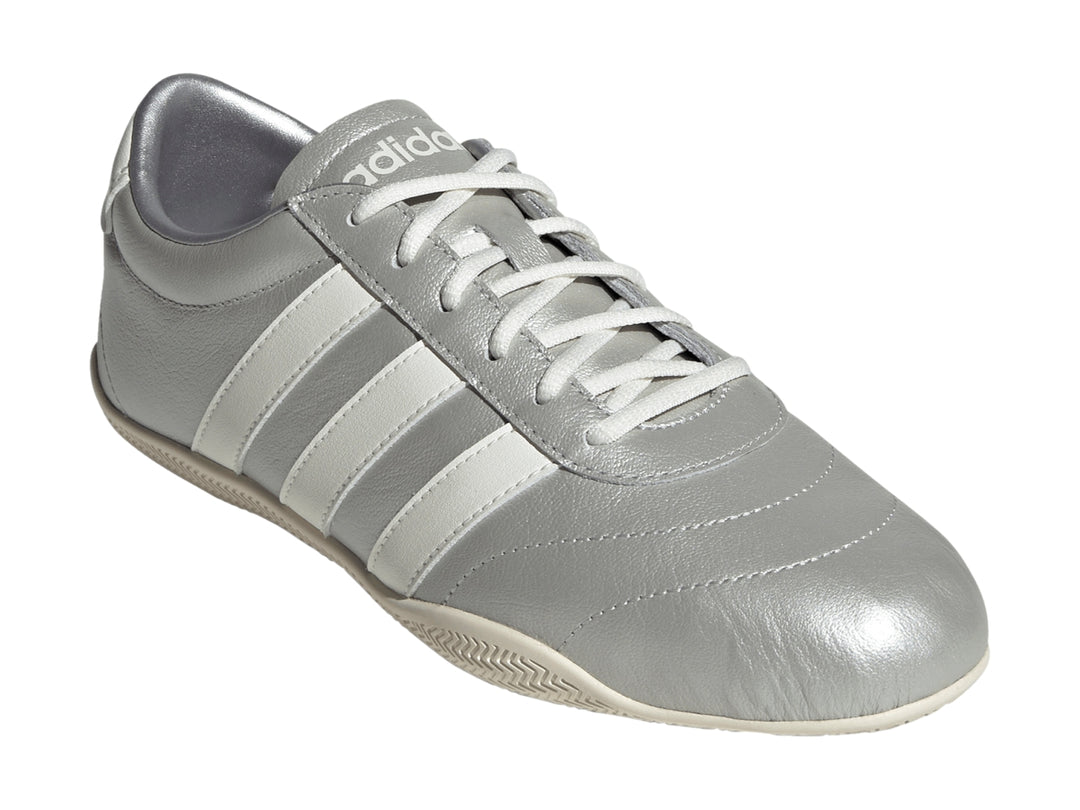 Tenis Adidas Grand Court Low en color plata metálico con tres franjas blancas laterales y suela blanca.