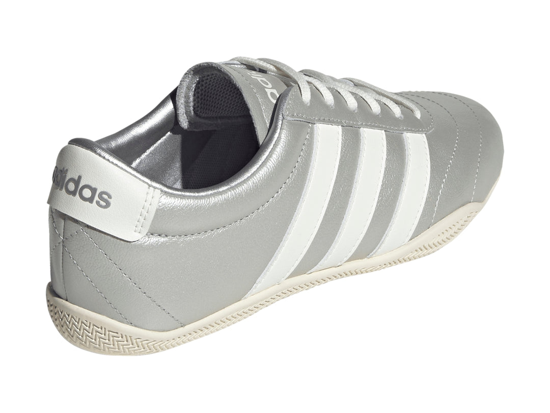Tenis Adidas Grand Court Low en color plata metálico con tres franjas blancas laterales y suela blanca.