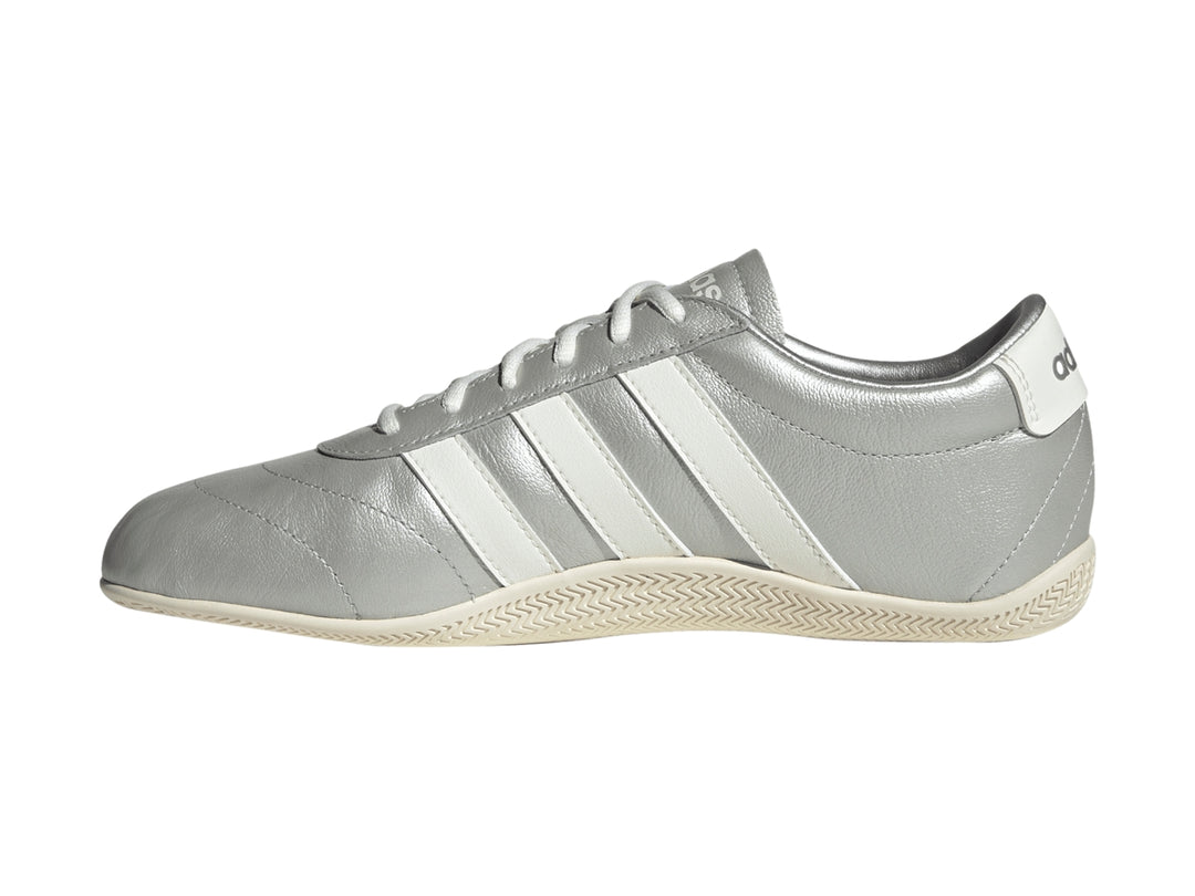 Tenis Adidas Grand Court Low en color plata metálico con tres franjas blancas laterales y suela blanca.