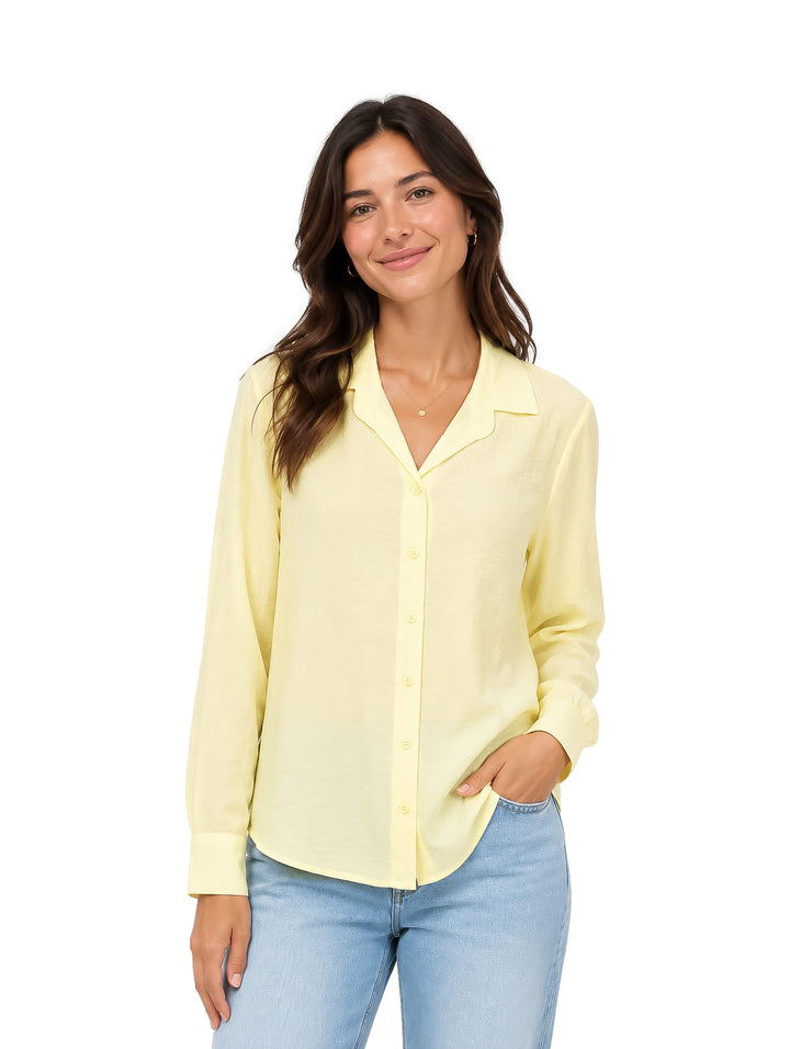 Mujer vistiendo una camisa de color amarillo claro con botones y manga larga.