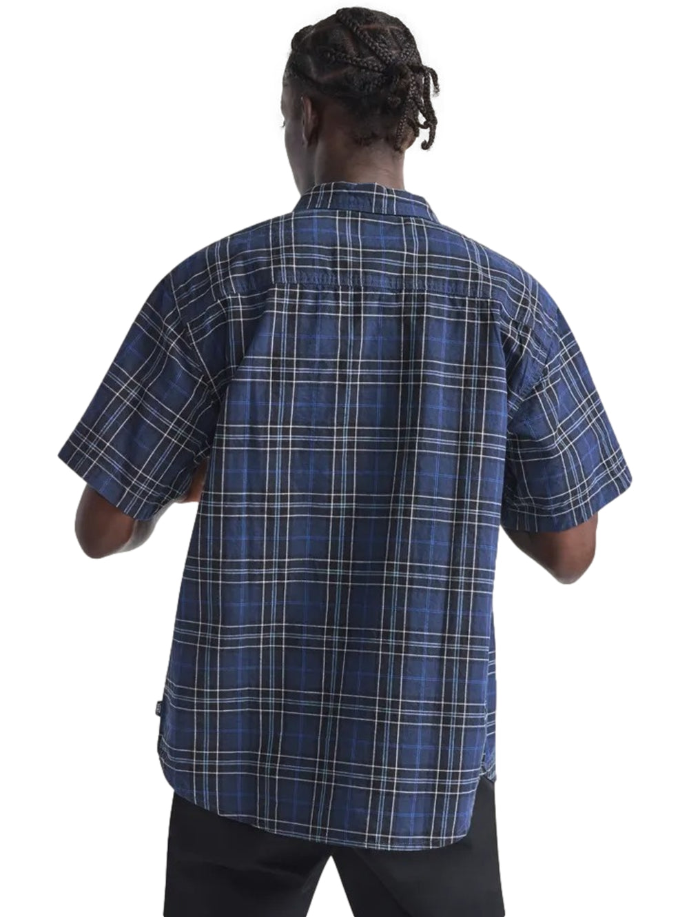 Hombre vistiendo una camisa de cuadros azul marino y negro de manga corta abierta sobre una camiseta blanca.