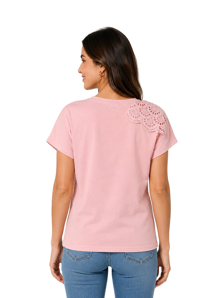 Mujer vistiendo camiseta rosa de manga corta con detalle de encaje en el hombro y jeans azules.