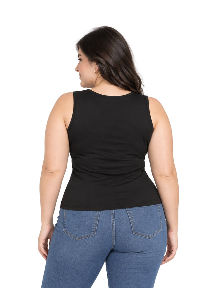 Mujer vistiendo una blusa negra sin mangas de cuello redondo y pantalones vaqueros azules.