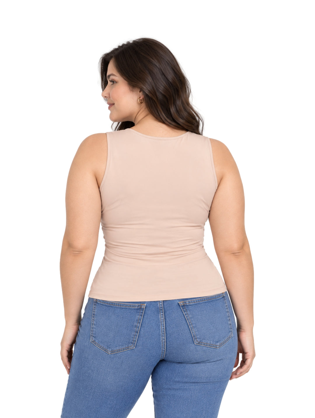 Mujer vistiendo una blusa sin mangas color champagne ajustada y pantalones de mezclilla azules.