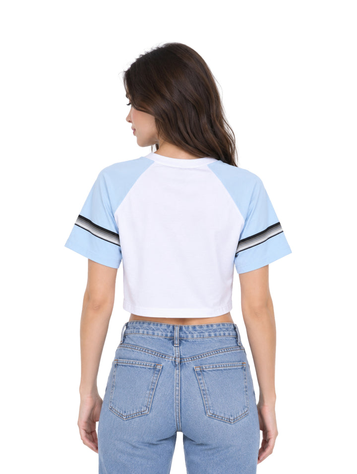 Mujer vistiendo un top corto blanco y azul con el número 08 en el pecho y jeans azules.
