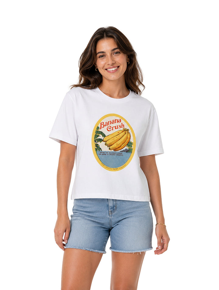 Mujer vistiendo playera blanca de manga corta con estampado circular de bananas en el pecho.