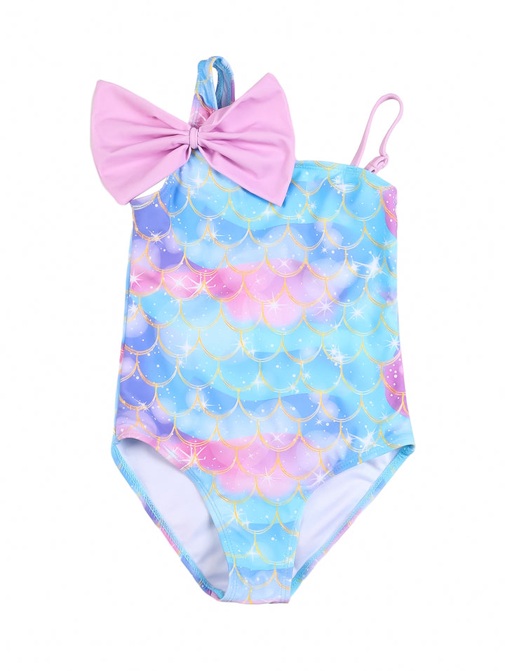 Traje de baño enterizo para niña con estampado de escamas de sirena en azul y rosa y un moño rosa en el hombro.