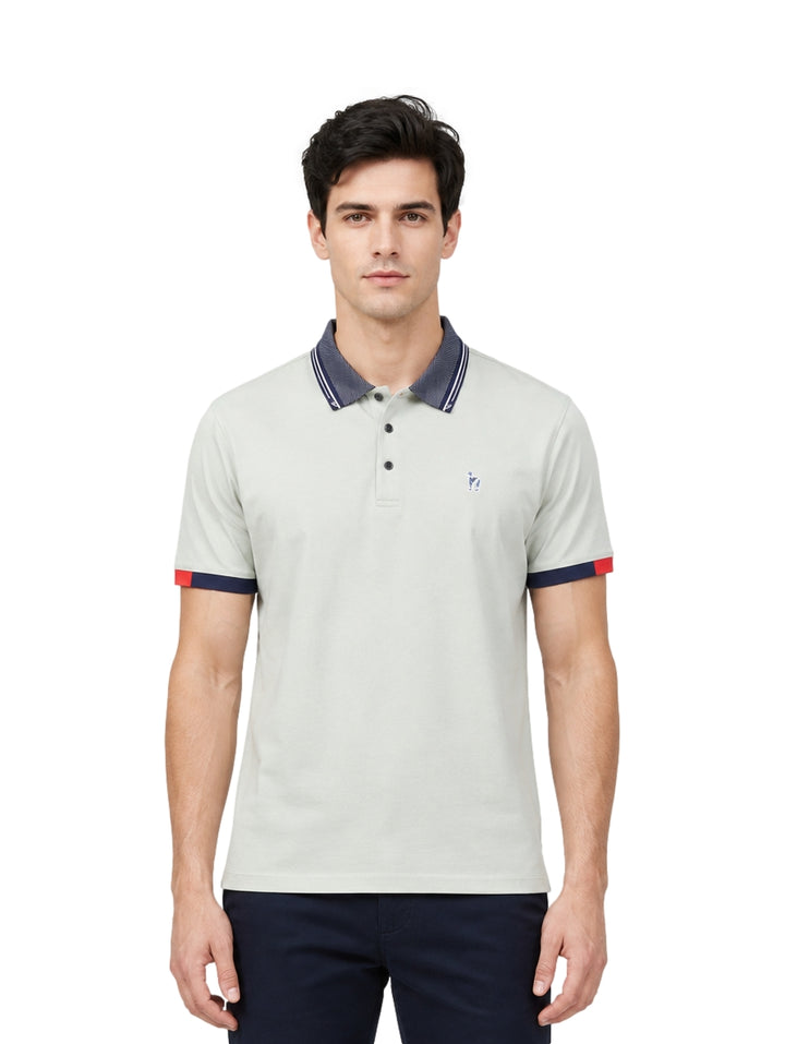 Hombre usando playera polo Pavini color verde claro con cuello y puños en azul marino y detalle rojo.