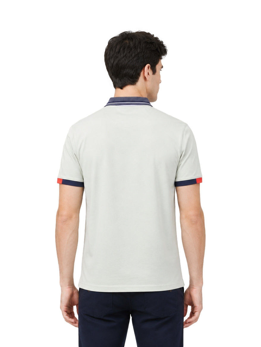 Hombre usando playera polo Pavini color verde claro con cuello y puños en azul marino y detalle rojo.
