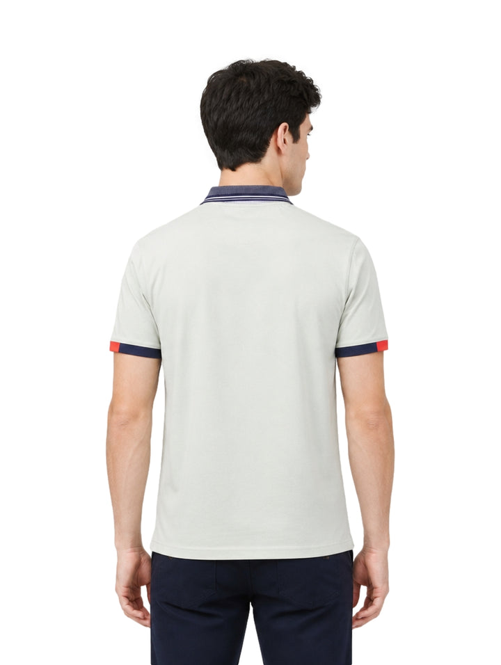 Hombre usando playera polo Pavini color verde claro con cuello y puños en azul marino y detalle rojo.