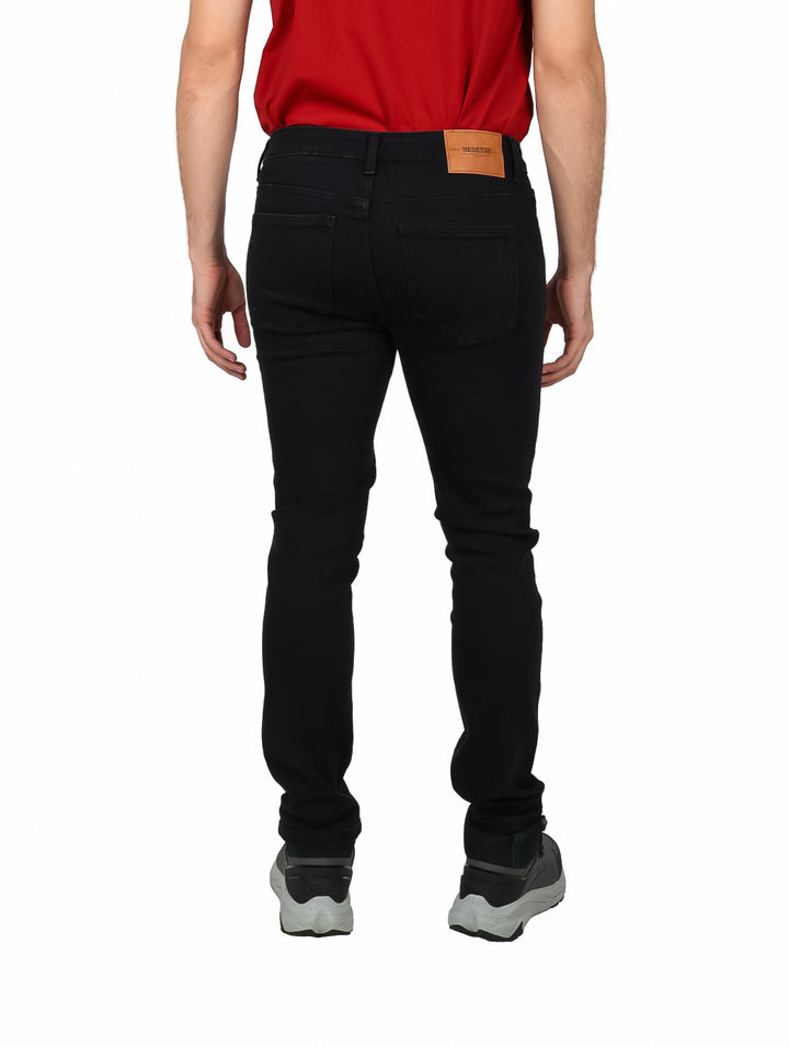 Hombre vistiendo pantalones jeans color negro de corte ajustado y camiseta roja.