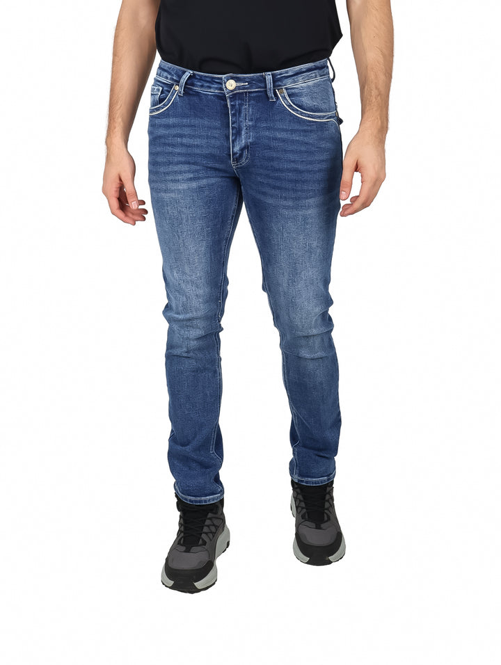 Hombre vistiendo jeans azul medio marca Deia Vu con calzado negro sobre fondo blanco.