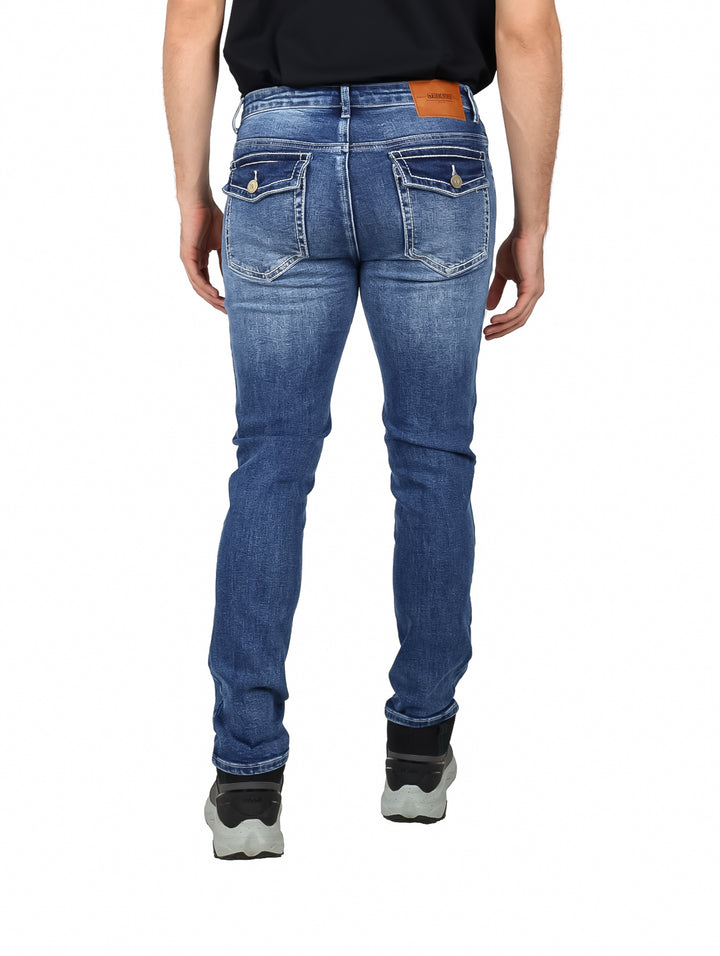 Hombre vistiendo jeans azul medio marca Deia Vu con calzado negro sobre fondo blanco.