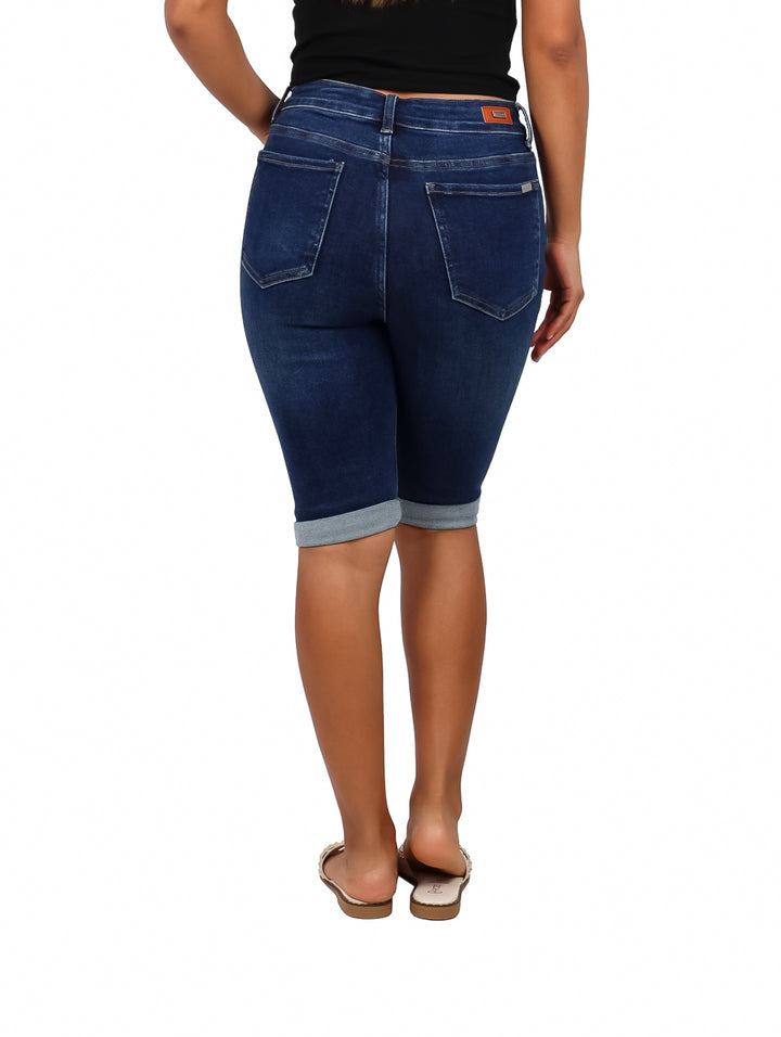 Mujer vistiendo pantalón capri de mezclilla color azul oscuro con detalles desgastados.
