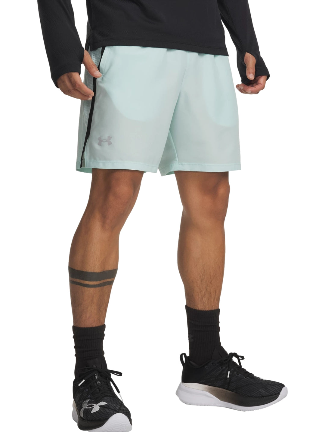 Hombre vistiendo shorts deportivos Under Armour color verde menta con franja lateral negra.