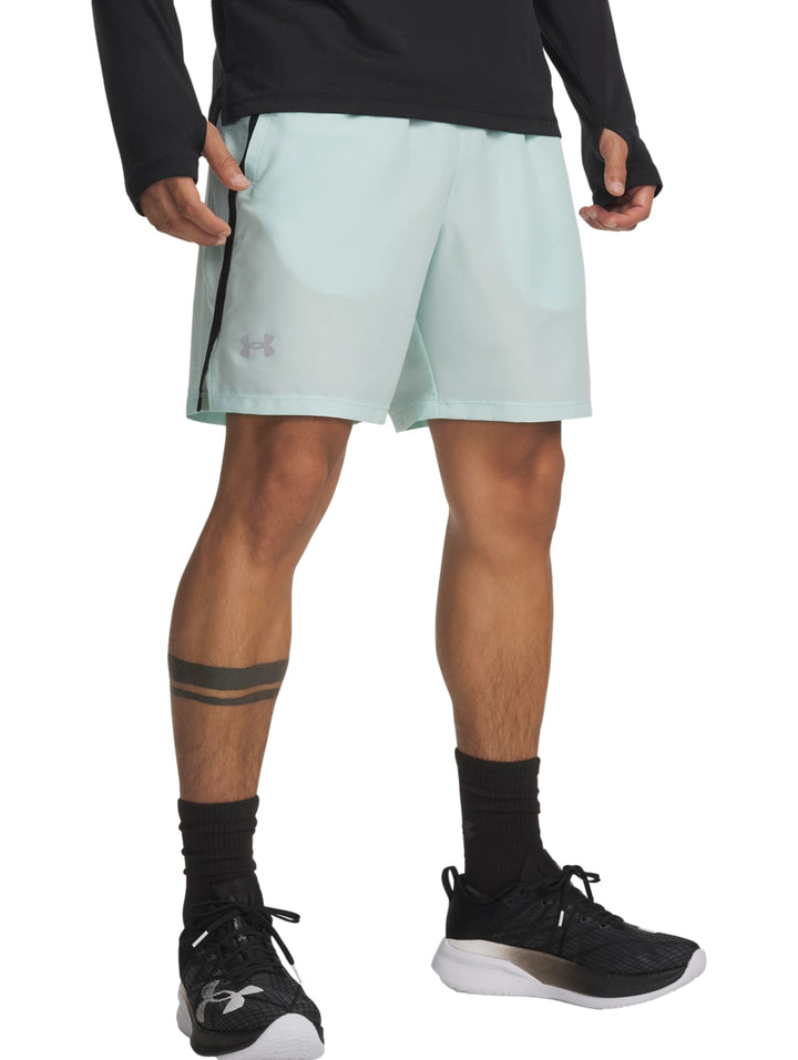 Hombre vistiendo shorts deportivos Under Armour color verde menta con franja lateral negra.