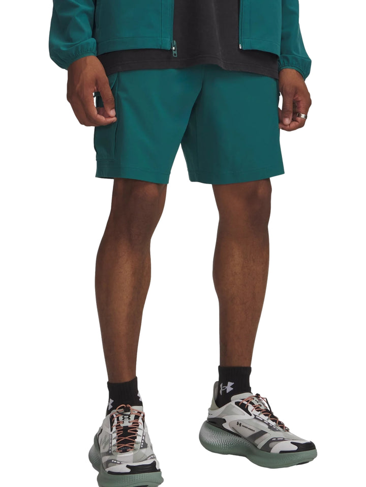 Hombre vistiendo shorts cargo color verde oscuro de la marca Under Armour.