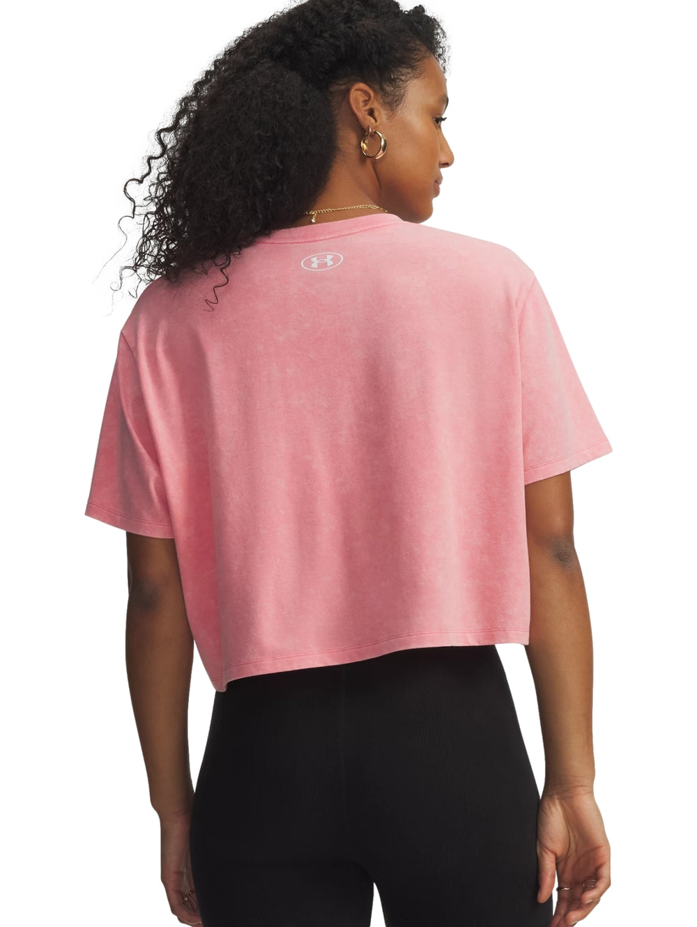 Mujer vistiendo una camiseta deportiva rosa de corte boxy de la marca Under Armour.