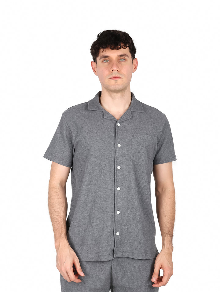 Hombre vistiendo una camisa casual de color gris oxford con botones blancos y manga corta.