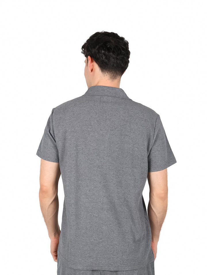 Hombre vistiendo una camisa casual de color gris oxford con botones blancos y manga corta.