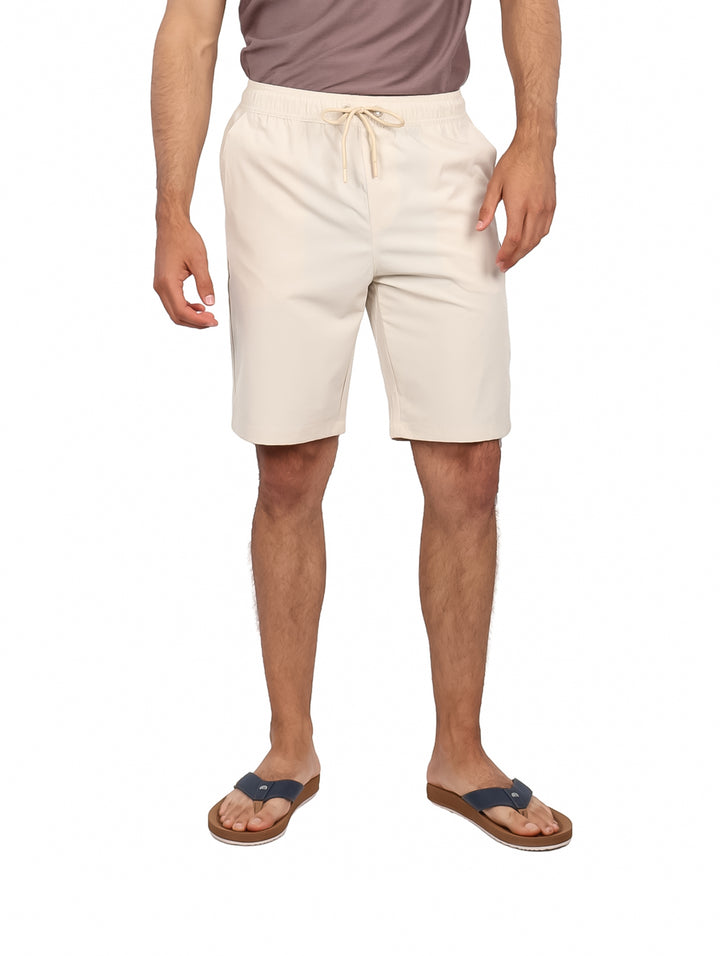 Hombre vistiendo bermudas color hueso con cintura elástica y cordón ajustable.