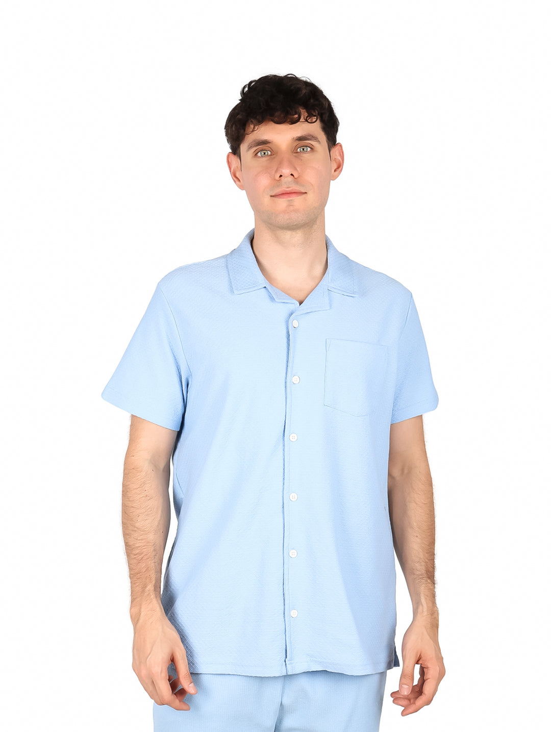 Hombre vistiendo una camisa de manga corta color azul claro con botones frontales.