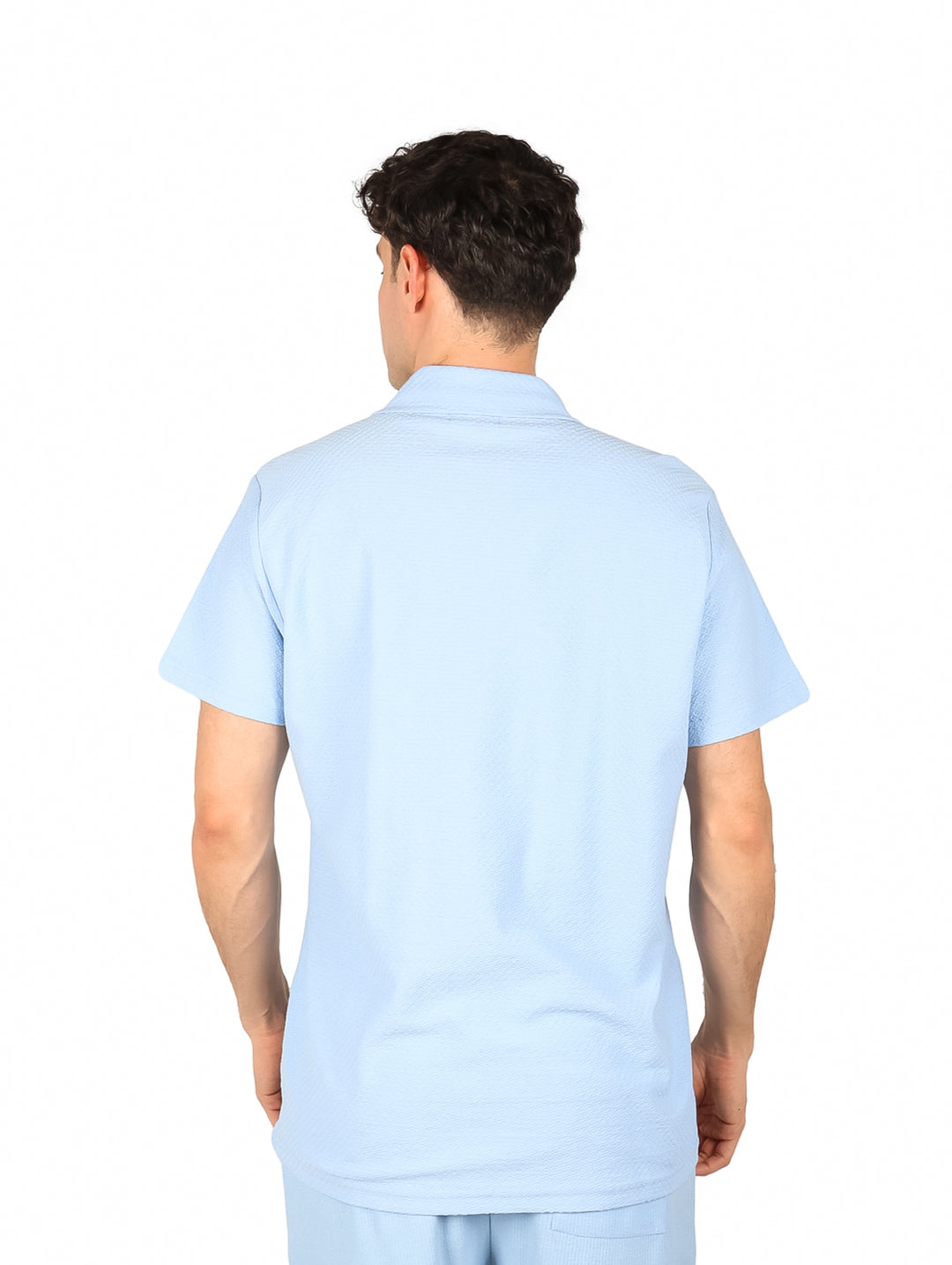 Hombre vistiendo una camisa de manga corta color azul claro con botones frontales.