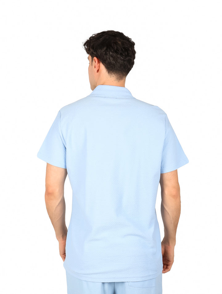 Hombre vistiendo una camisa de manga corta color azul claro con botones frontales.