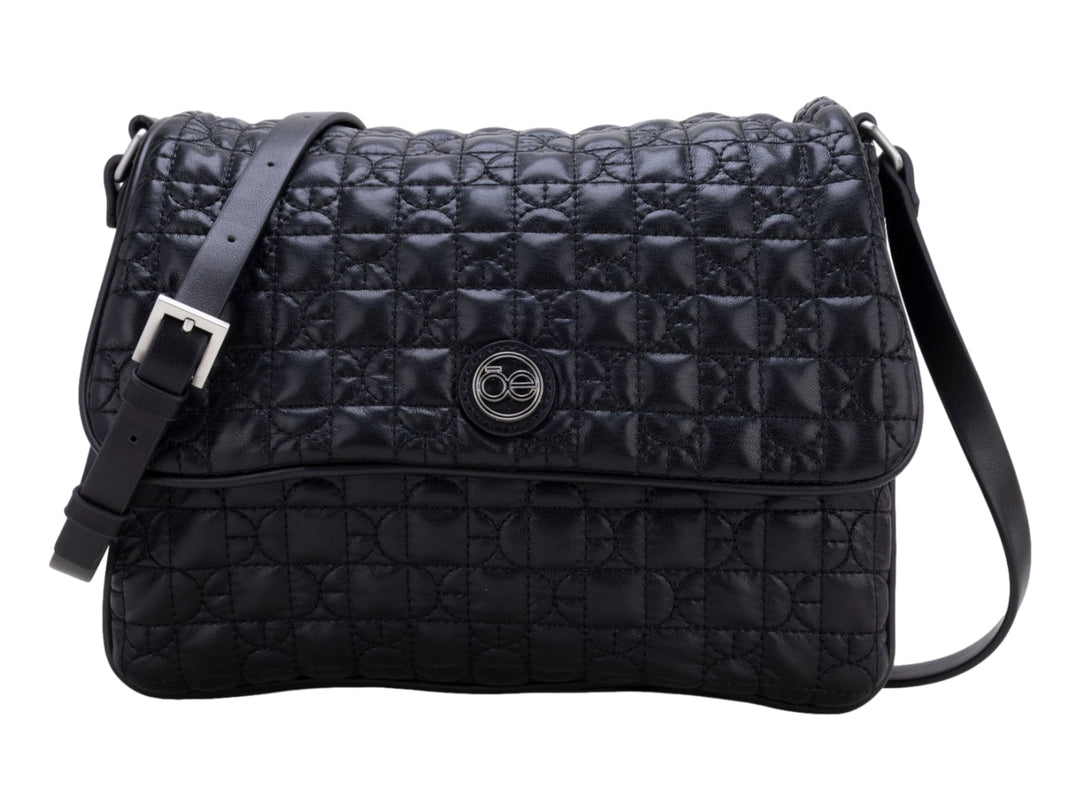 Bolso de hombro color negro con textura acolchada geométrica, correa ajustable y detalle circular central.