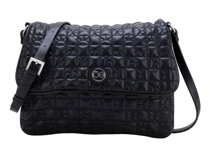 Bolso de hombro color negro con textura acolchada geométrica, correa ajustable y detalle circular central.